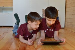 Two children looking at a tablet on the floor