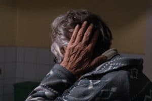 An older person holds their head