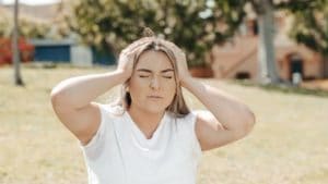 A woman holds her head in pain