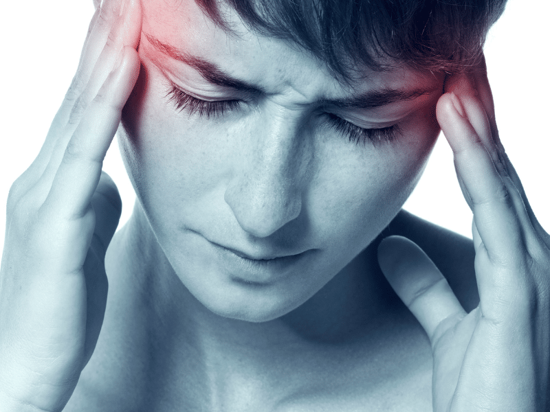 A woman rubbing her temples while experiencing a painful migraine